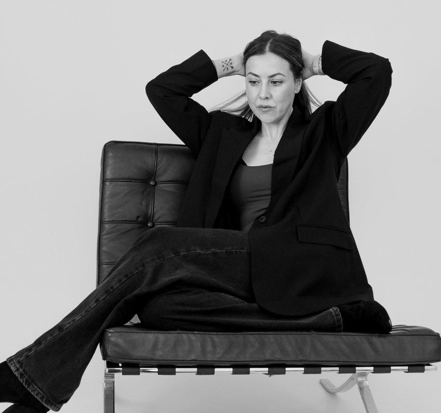 Adele Molyneux sitting in a black leather chair, hands behind her head